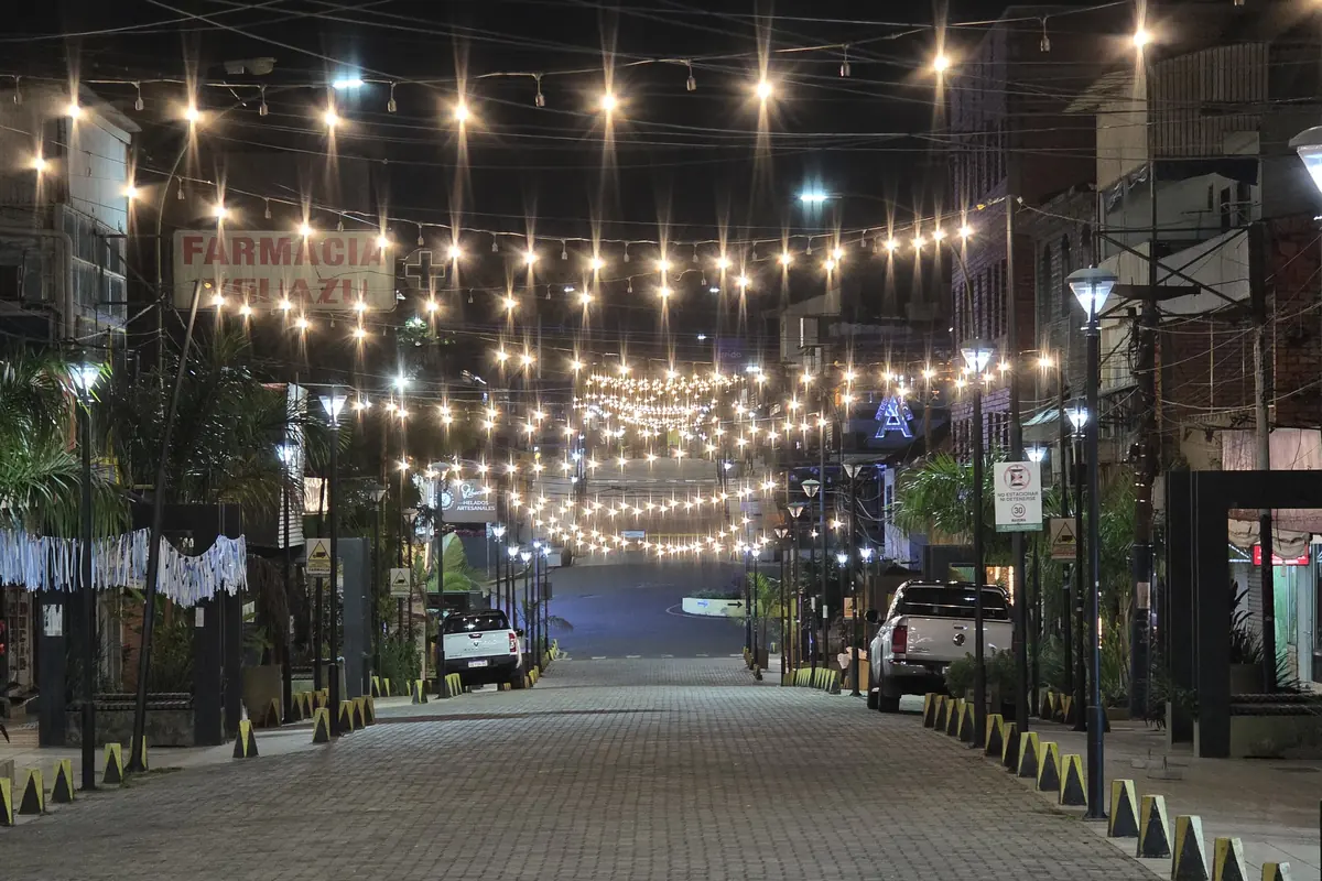Avenida Brasil in Puerto Iguazú at night, a cobbled street under strings of lights with palms on both sides